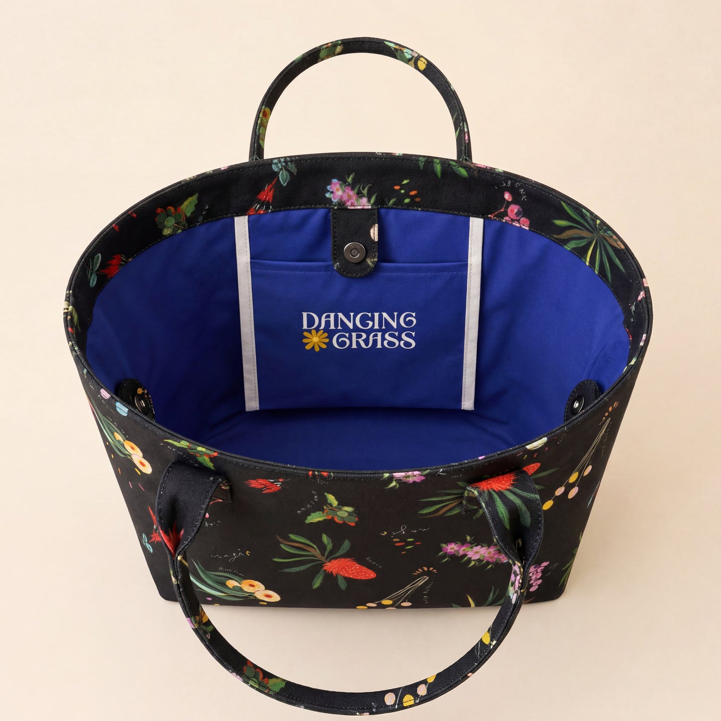 Australian Floral-patterned bag with a blue interior and 'Dancing Grass' logo on a beige background