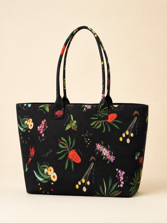 Black tote bag with colorful floral australian patterns on a beige background