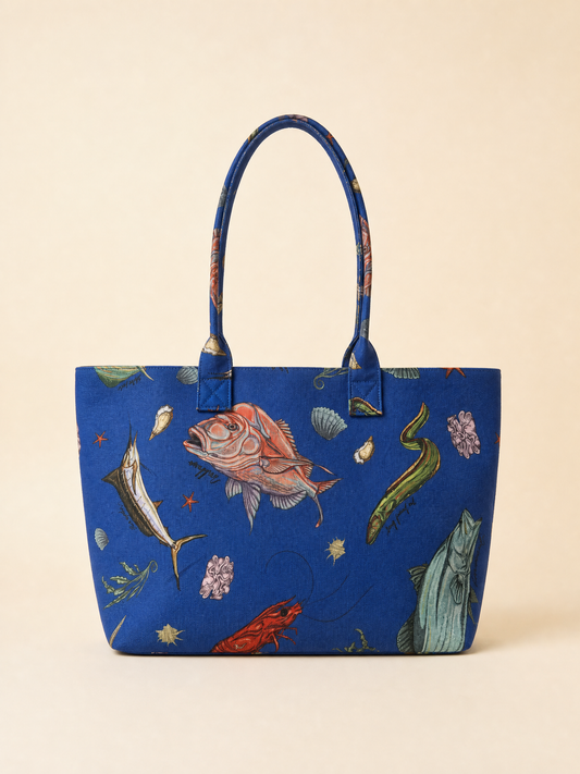 Blue tote bag with australian fish and plant designs on a beige background