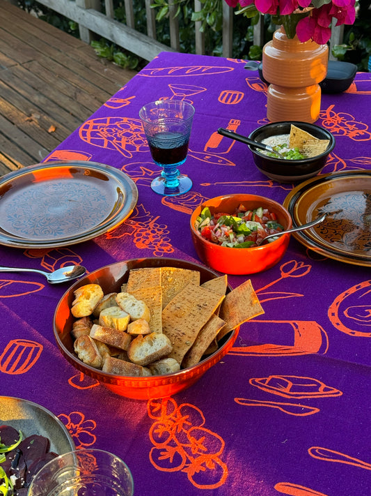 Purple tablecloth elegantly laid out with a dining setup, featuring plates, cutlery, and an array of food.