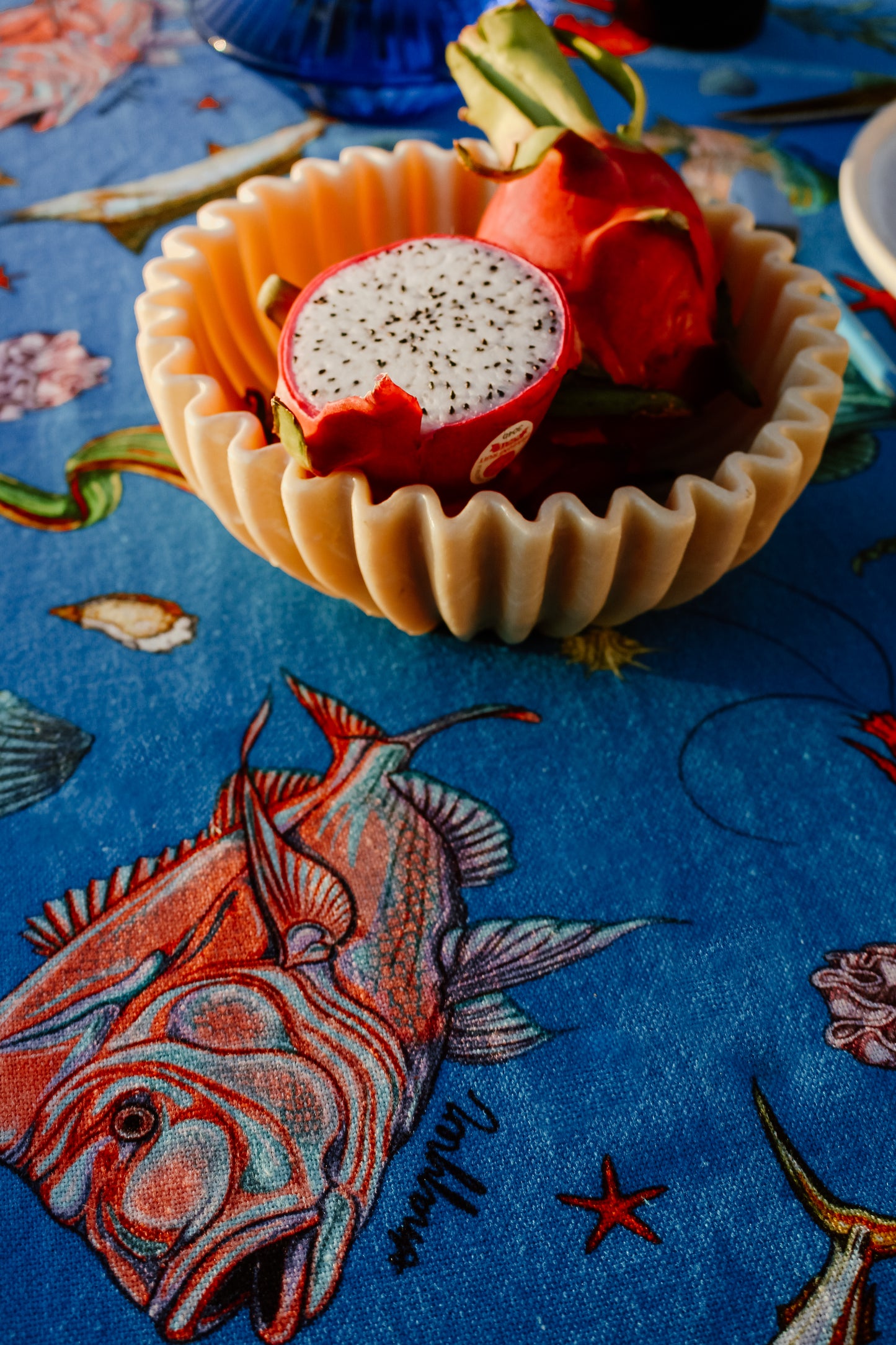 A decorative bowl filled with dragon fruit sits atop the Fishing for Fishes funky tablecloth, highlighting the intricate fish and coral patterns in close detail