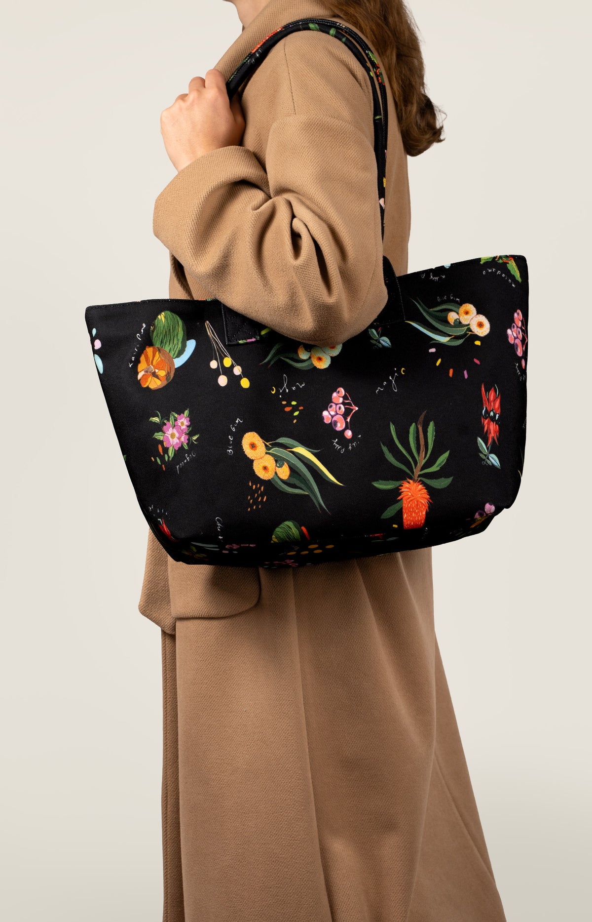 Model in a camel coat with the Dark Flora Dancing Grass shoulder bag