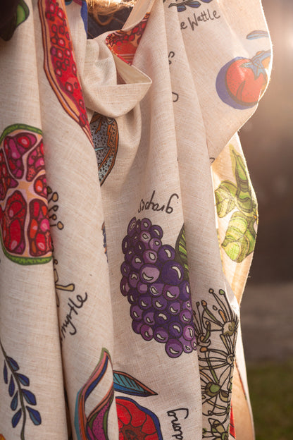 Sunlit close-up of a draped tablecloth with detailed prints of colorful fruits and vegetables, highlighting the fabric's natural texture