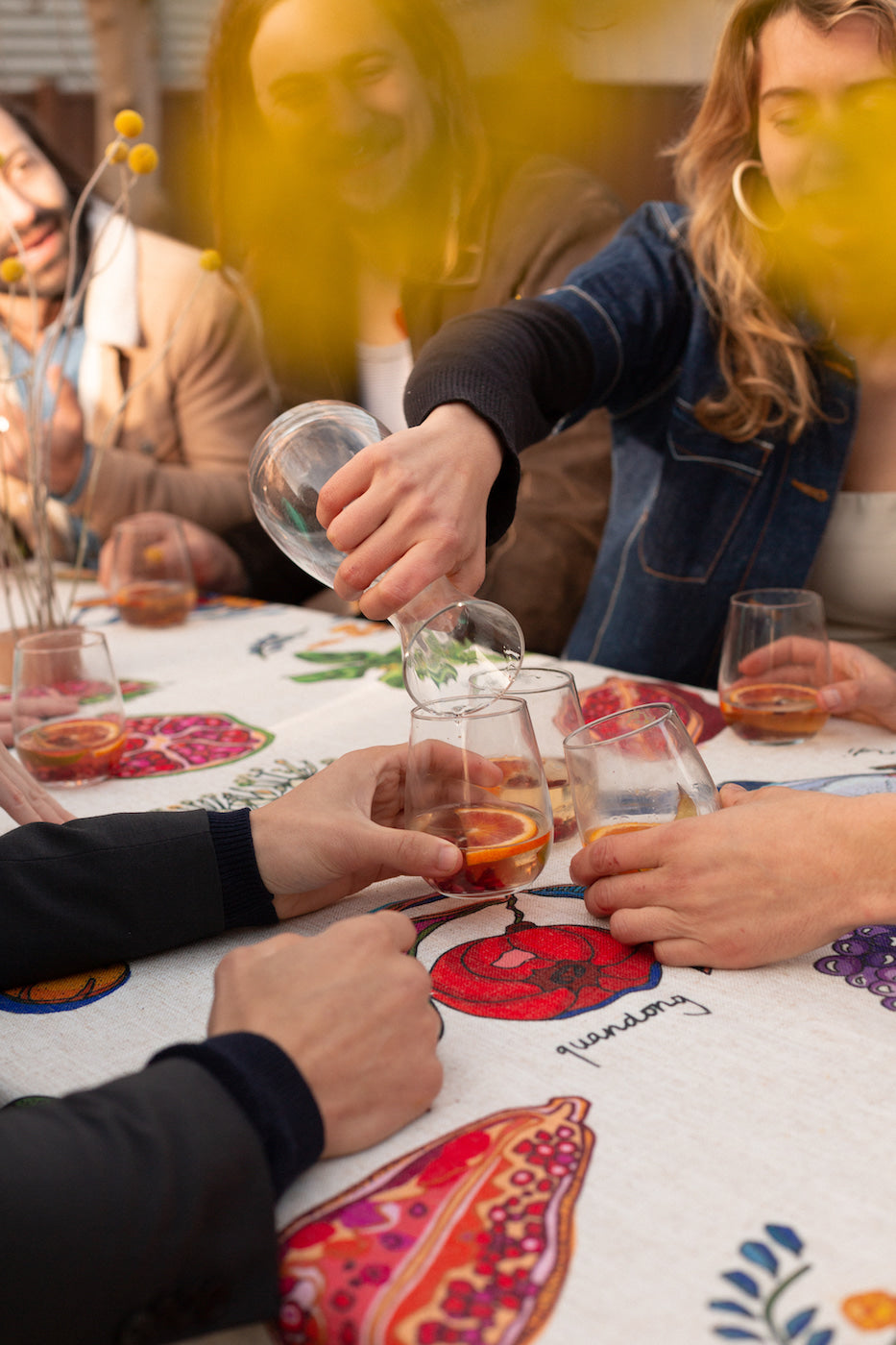 A detailed view of a linen tablecloth displaying vibrant illustrations of Australian bush foods, including lemon myrtle, finger lime, and barramundi fish.